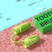 Green dog toothbrush with bristles on a red and green checkered surface.