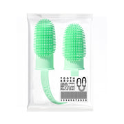 Two green silicone toothbrushes in packaging with a white background